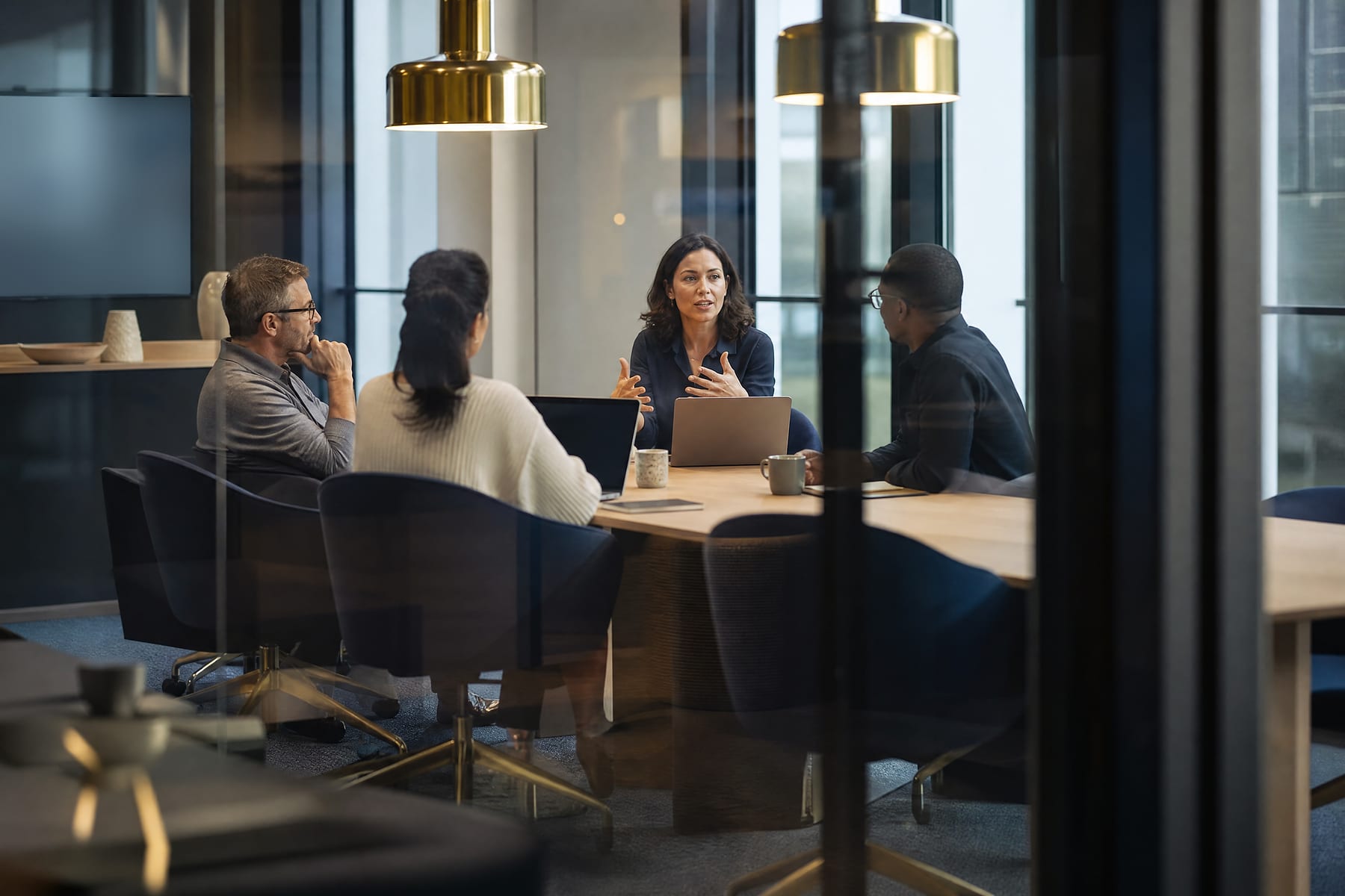 Colleagues in a candid strategy meeting in a glass-walled meeting room